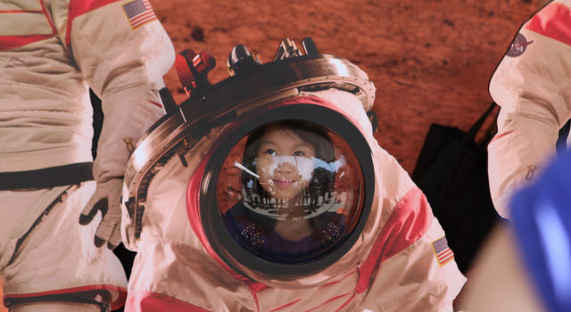 A young visitor at Explore JPL poses with a cutout of an astronaut on Mars.
