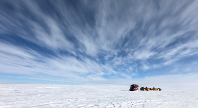 NASA scientists traverse Antarctica's icy landscape, towing scientific instruments and cold-weather gear with them
