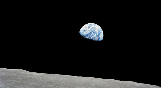 The Earth rises above the lunar horizon in this telephoto view taken from the Apollo 8 spacecraft