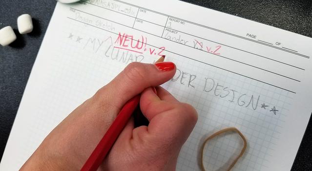 Sketch of a lunar lander on graph paper with red writing that reads, "NEW v. 2"