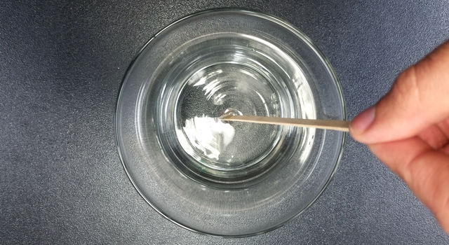 Warm water being stirred in a glass jar