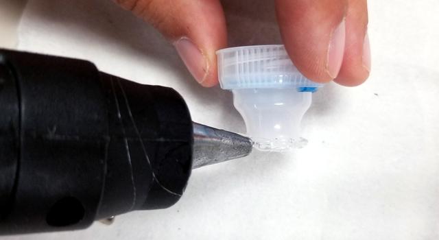 Placing a bead of glue along the circumference of the bottle top