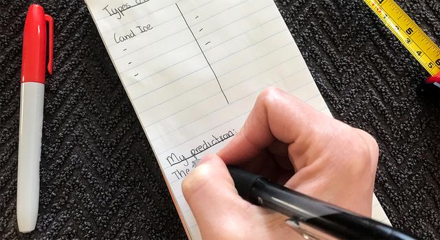 Person writing down their prediction on a notepad