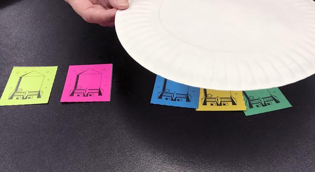 Three rocket cutouts under a paper plate, two out from under the plate