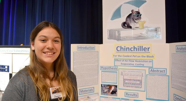A student stands in front of her science fair project poster