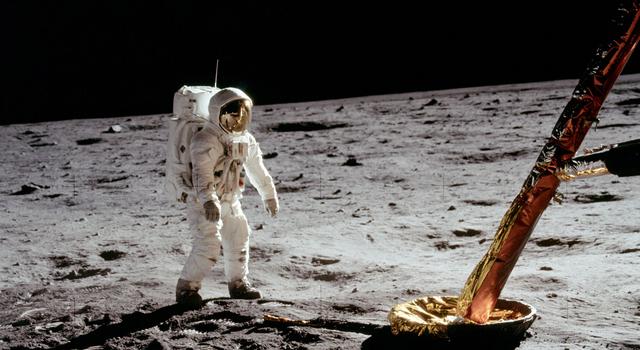 An Apollo 11 astronaut stands on the Moon and one of the legs of the lunar module can be seen in the corner of the image