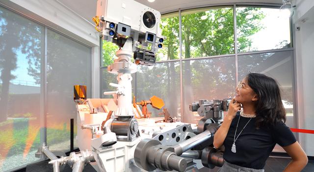 Michelle Vo poses for a photo in front of a full-size model of the Curiosity Mars rover at JPL.