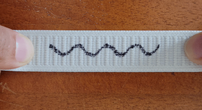 A wavy line drawn on a piece of elastic stretches out as the elastic is pulled.