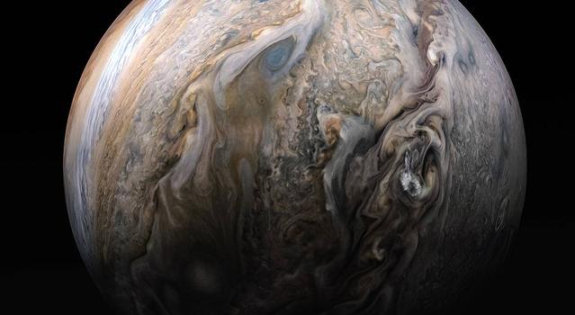 Intense swirls of clouds cut across Jupiter's colorful stripes of clouds and gas and move from from the bottom of the image to the top in this up-close side-view of Jupiter.